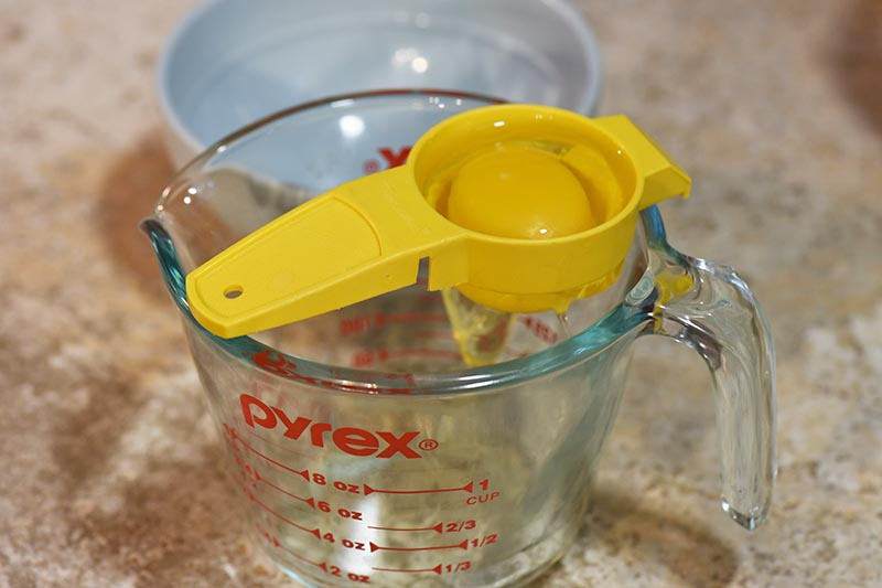 separating eggs using an egg yolk separator and a Pyrex measuring cup for chocolate cupcakes recipe