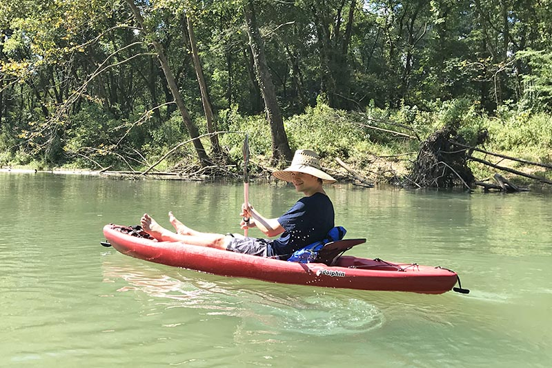 teen boy kayaking on the clear water of the Current River, one of the best float trips in Missouri