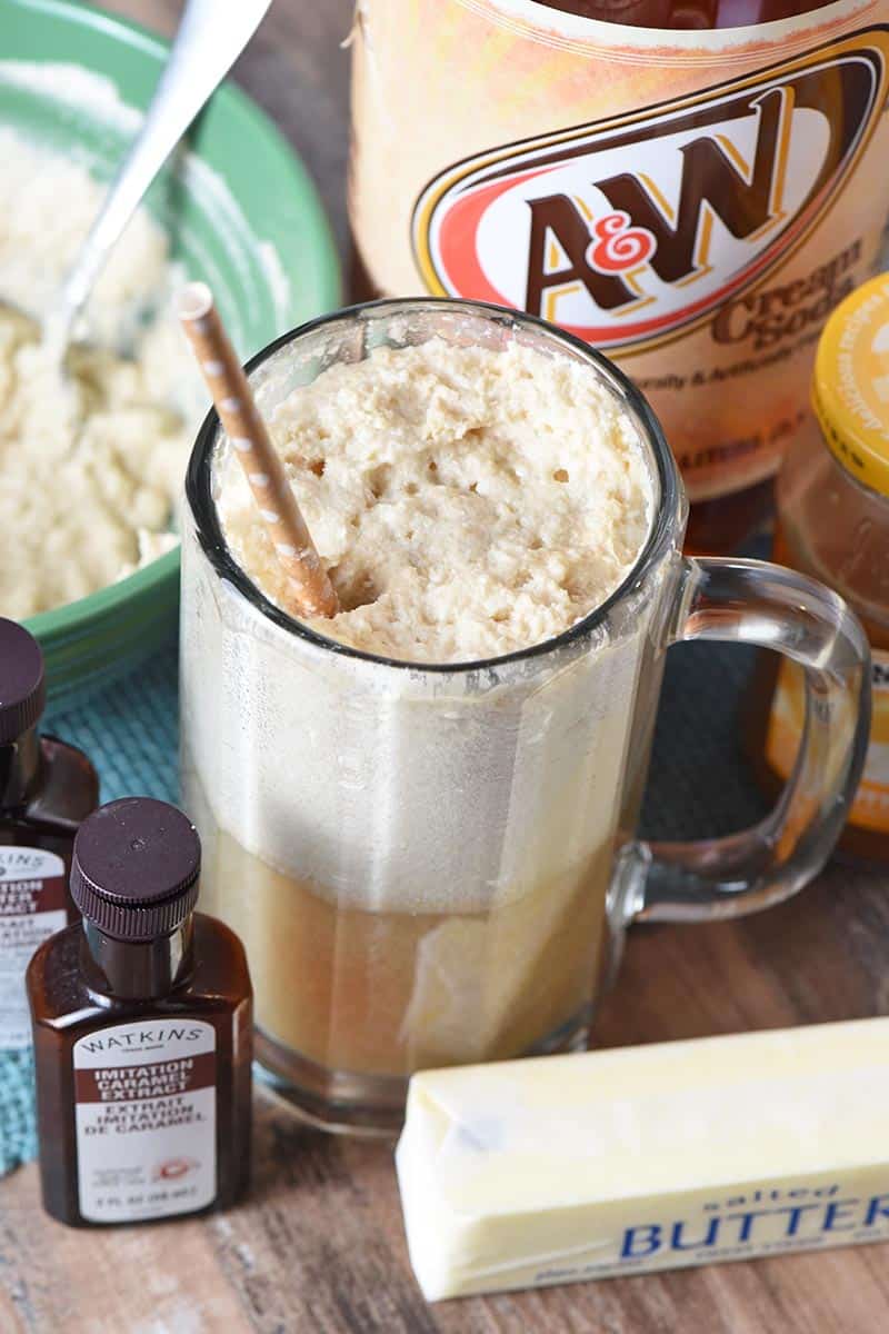 tall mug of cold butterbeer with ingredients for butterbeer recipe around it