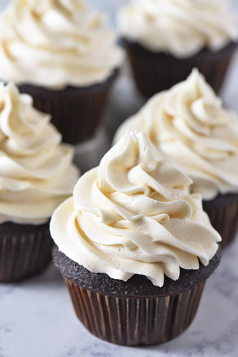 easy chocolate cupcakes with butterbeer buttercream frosting and brown paper cupcake liners on a white marble countertop