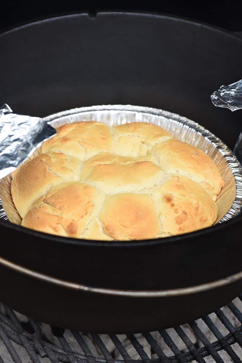 grilling Dutch oven drop biscuits on a camping grill with a foil pie plate and foil sling