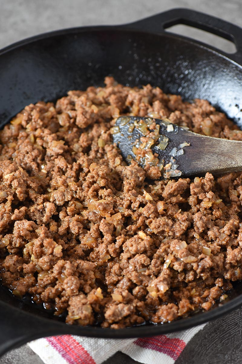 ground beef sloppy joes mixture in iron skillet with wooden spatula