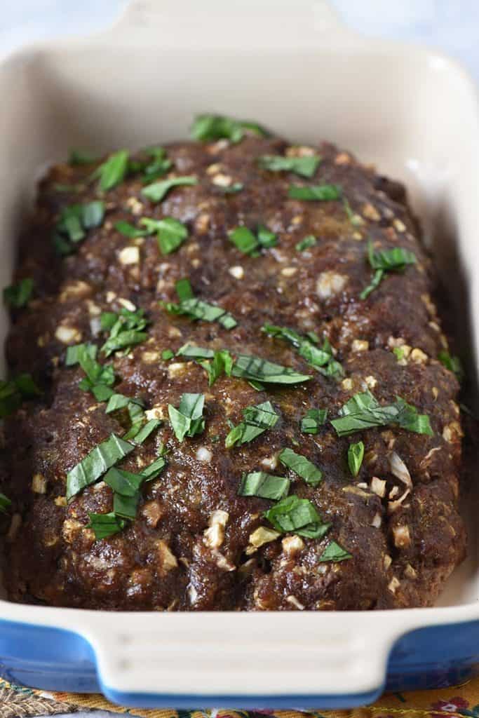low carb meatloaf baked in blue baking dish with basil sprinkled on top