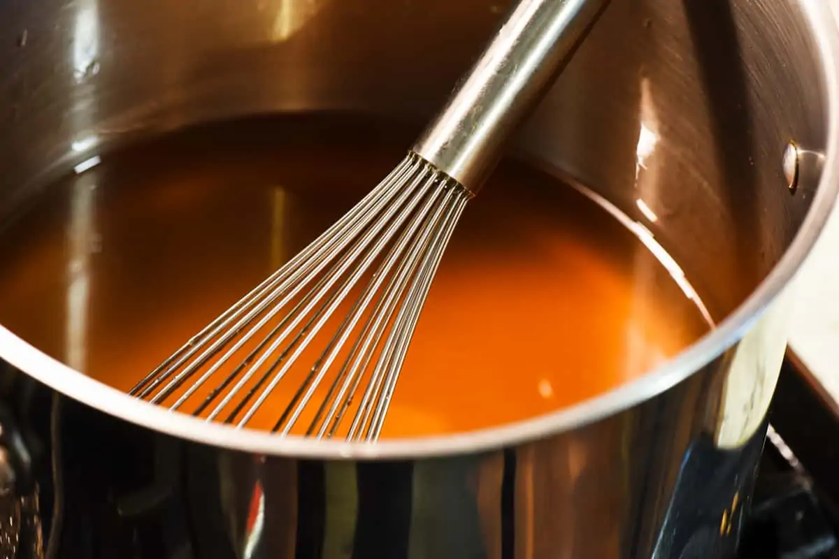 cooking apple jelly in a stock pot with a whisk