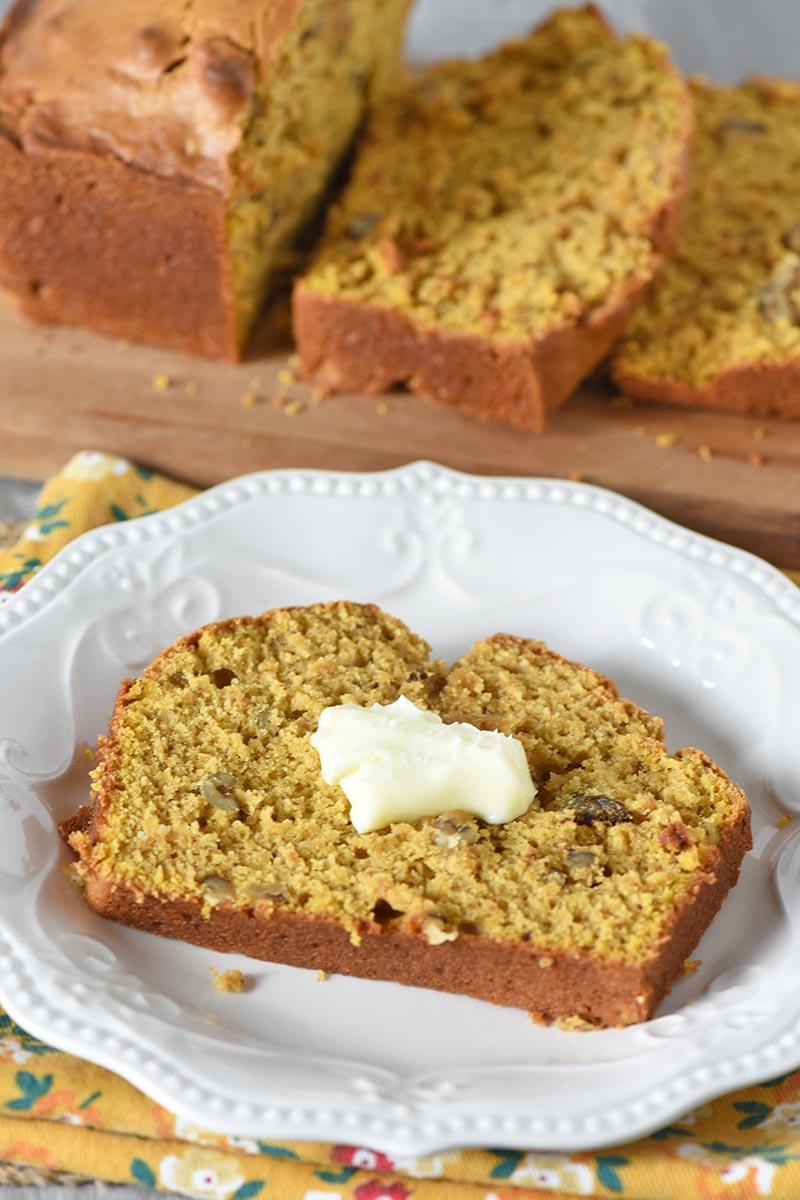 slice of pumpkin bread with butter on white plate