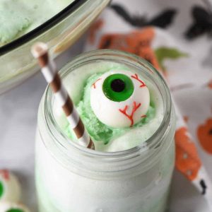 mason jar of Polyjuice Potion recipe with lime sherbet punch with candy eyeball and brown paper straw