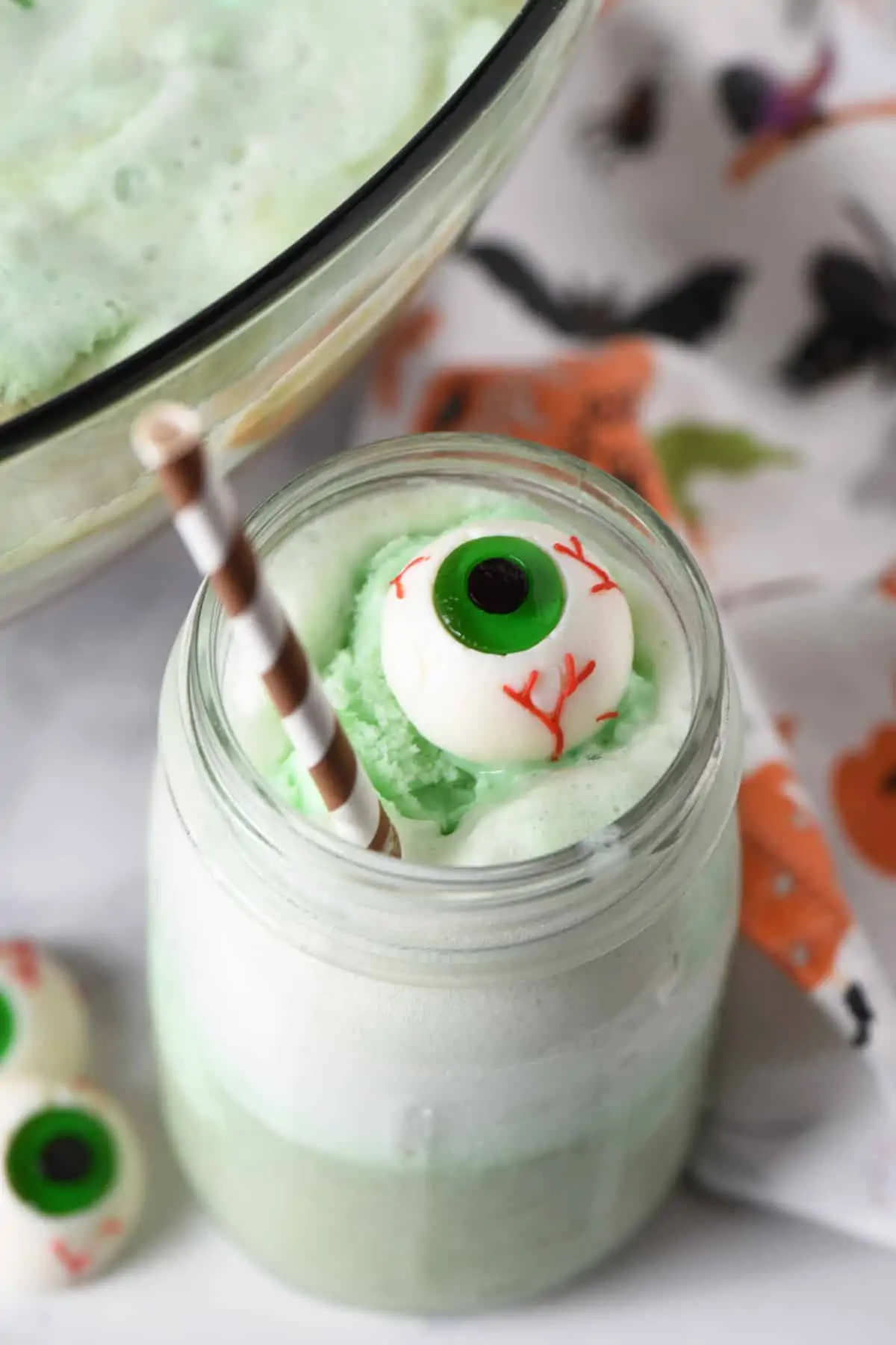 mason jar of Polyjuice Potion recipe with lime sherbet punch with candy eyeball and brown paper straw