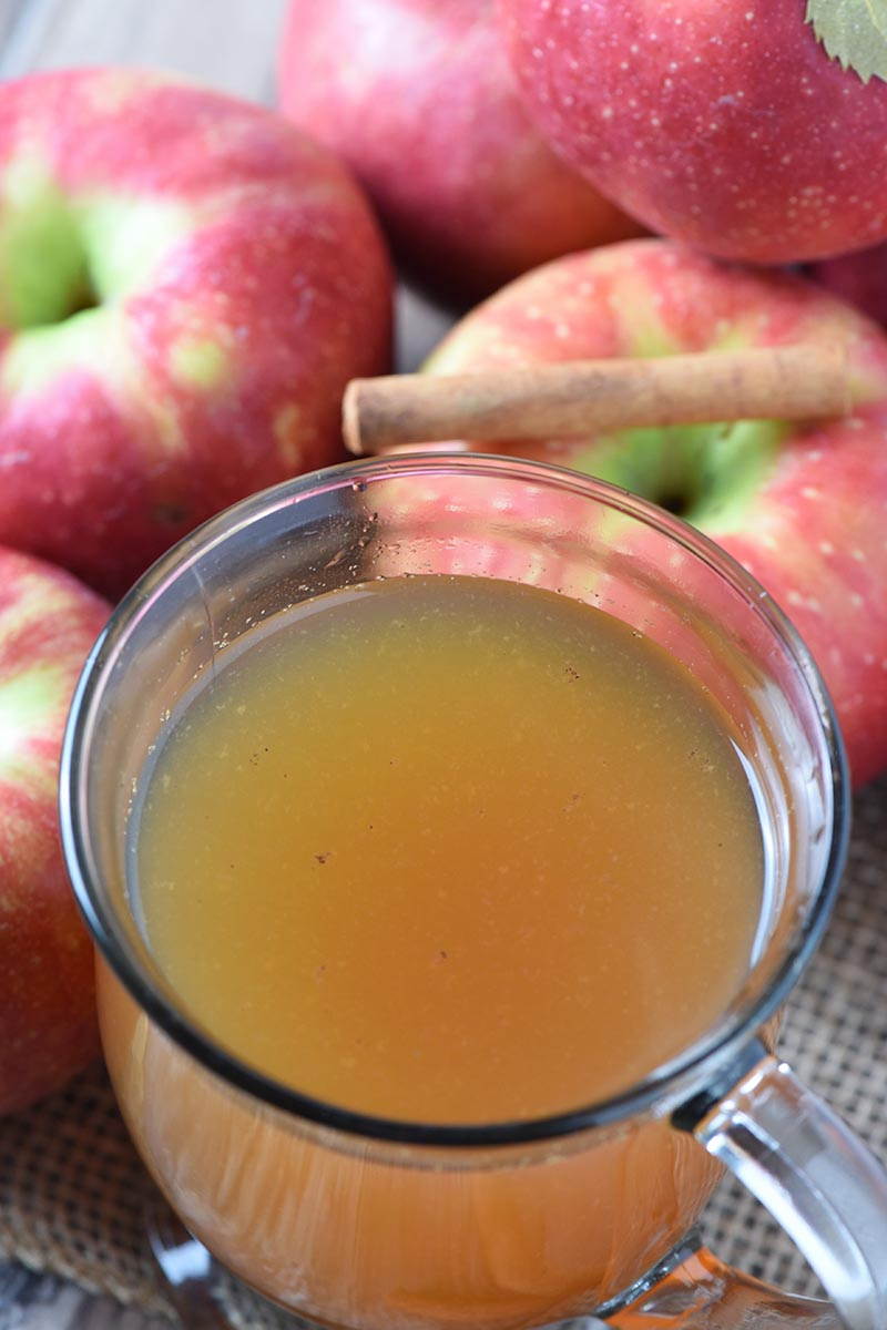 slow cooked mulled cider in a glass mug with apples