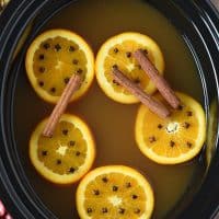 mulled cider with cinnamon sticks, oranges, and cloves in a slow cooker