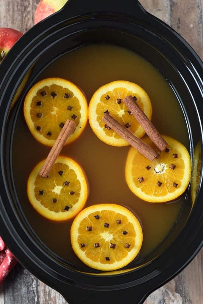 mulled cider with cinnamon sticks, oranges, and cloves in a slow cooker
