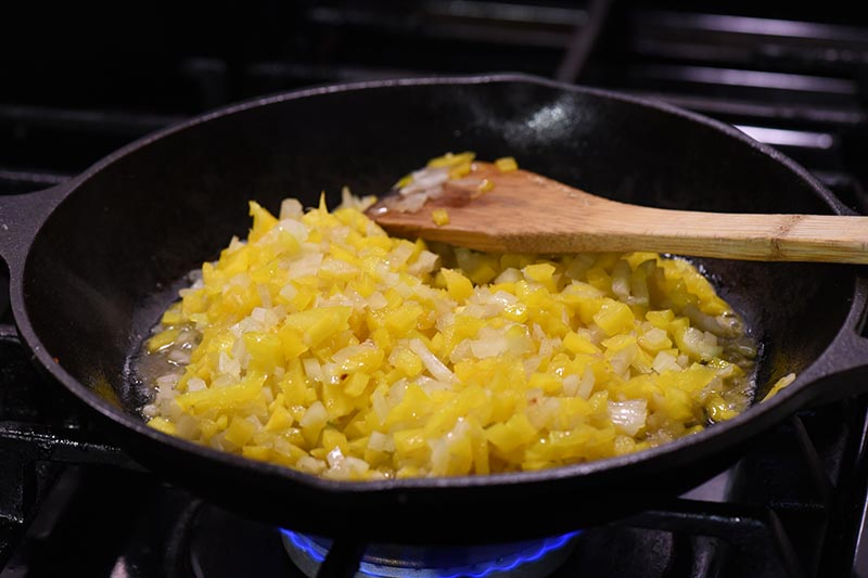 garlic, onions, and peppers minced and sautéing in cast iron skillet for taco sloppy joe recipe