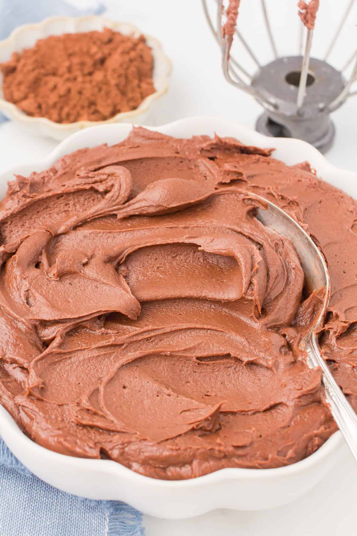chocolate buttercream with cocoa powder in a large white bowl with a spoon