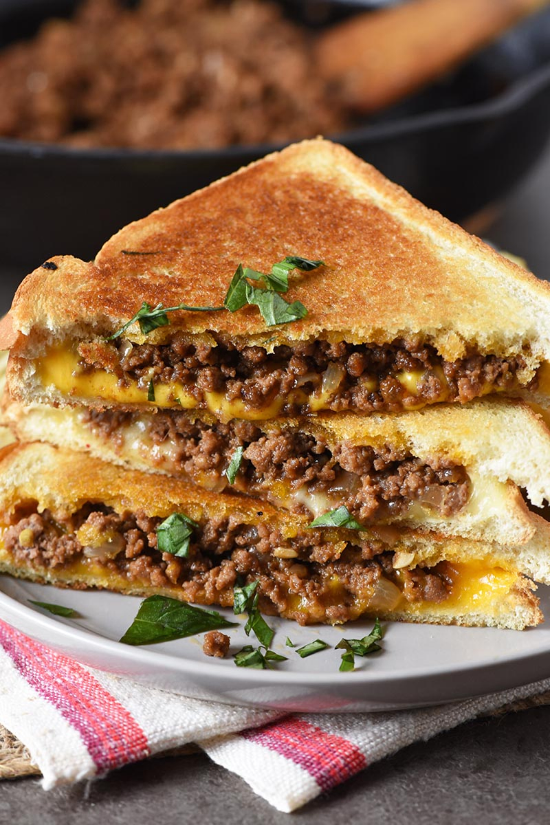 grilled cheese juicy burger or loose meat sandwich with fresh basil on gray plate