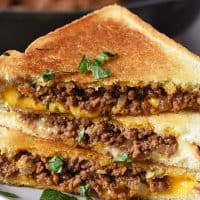 grilled cheese sloppy joes on butter bread with basil on gray plate
