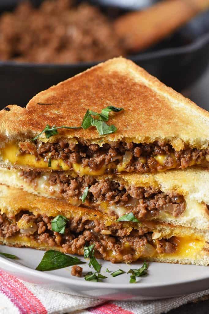 grilled cheese sloppy joes on butter bread with basil on gray plate