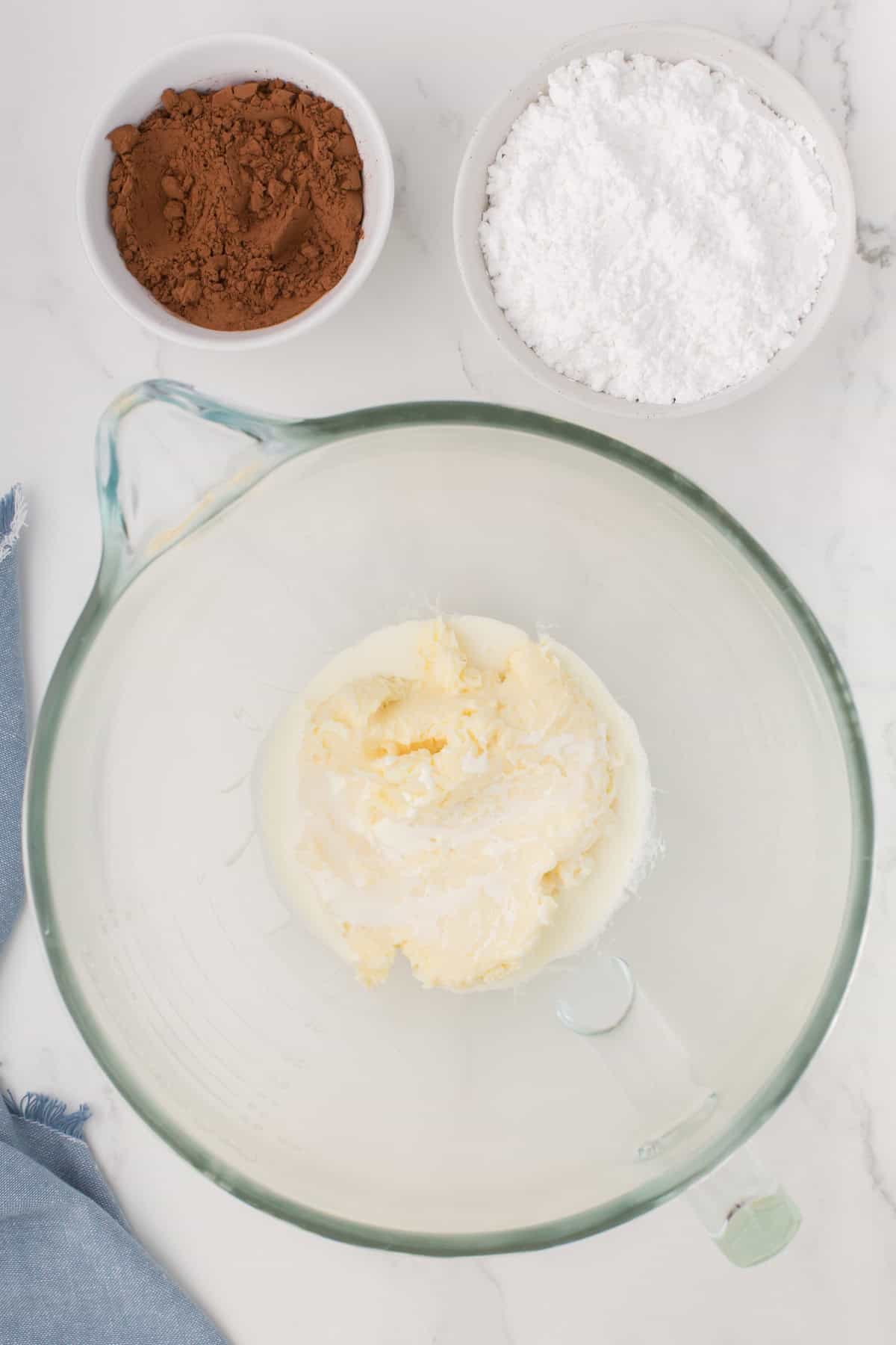 mixing up milk chocolate buttercream icing in a large glass mixing bowl