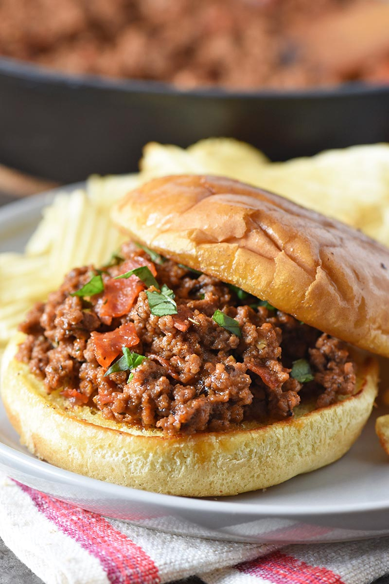 open faced pizza sloppy joes on toasted buns with potato chips, served on a gray plate
