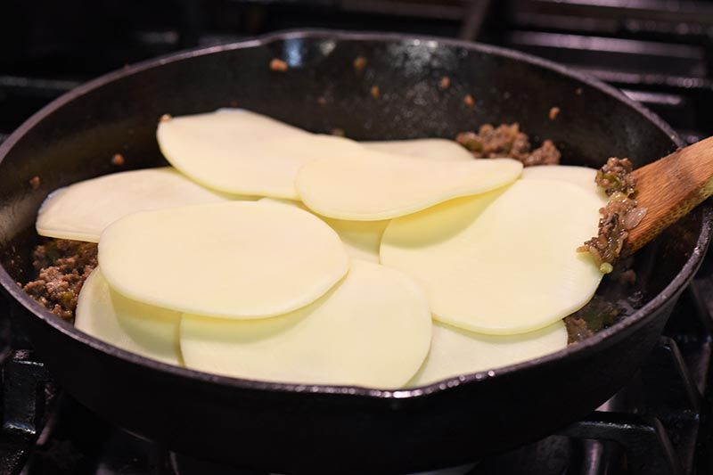 provolone cheese topping Philly cheesesteak sloppy joes meat in cast iron skillet