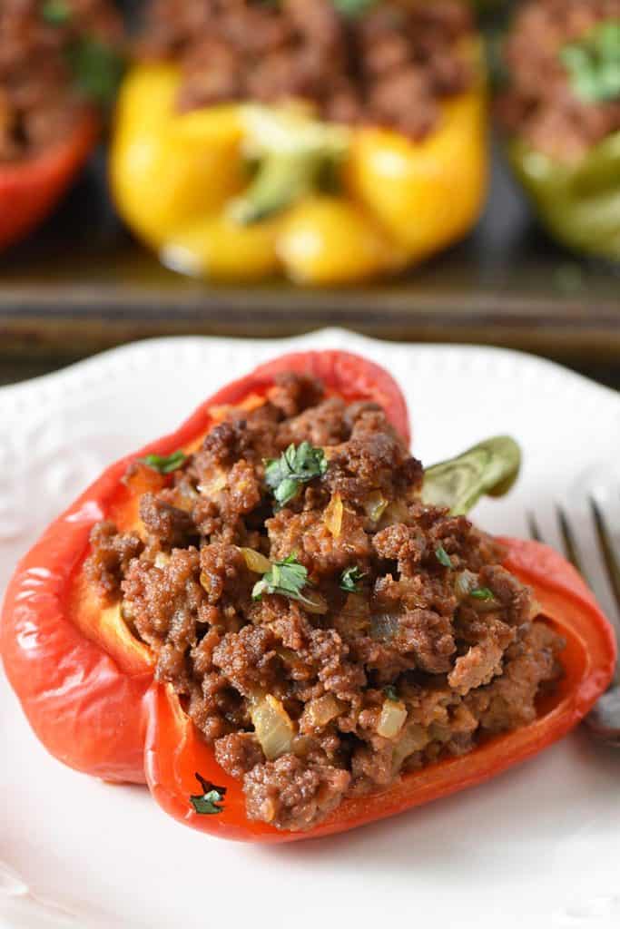 sloppy joe stuffed peppers on baking sheet and ivory plate
