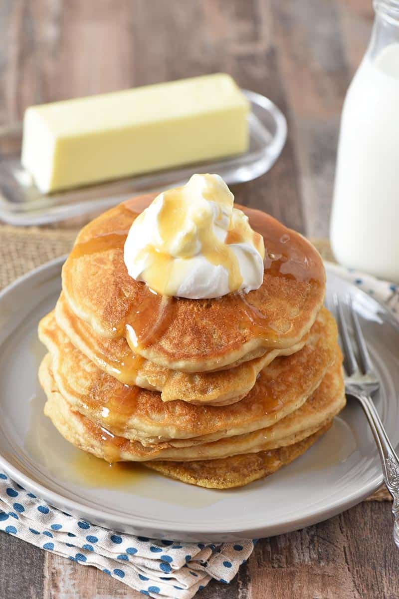 stack of butterbeer pancakes from scratch on gray plate with butter, milk, whipped cream, and butterscotch topping