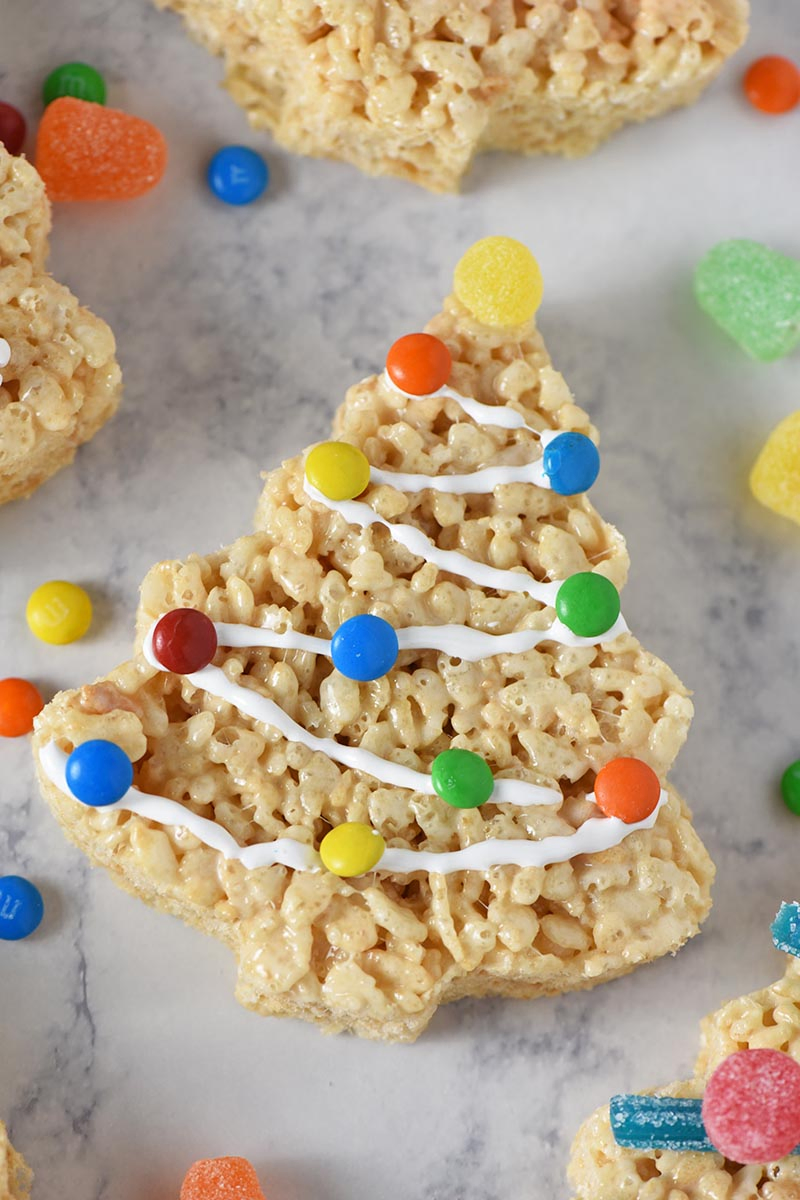 M&M's Minis and Marshmallow Fluff decorating a Christmas tree Rice Krispie treat on white marble countertop