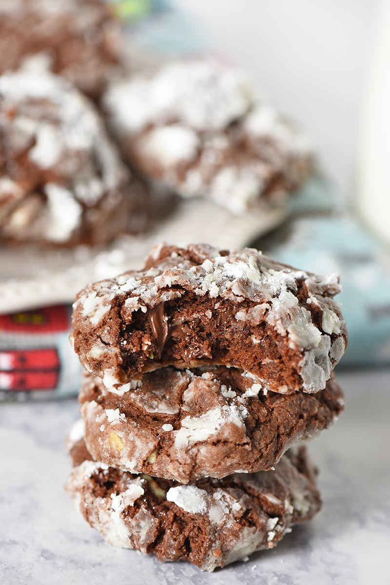 stack of chocolate crinkle cookies with bite taken out of Christmas cookie