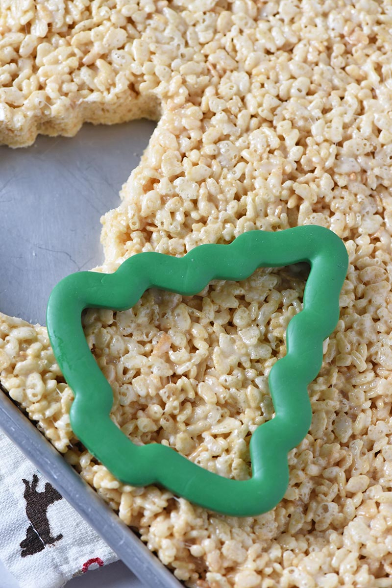 cutting out Christmas tree rice crispy treats with a cookie cutter