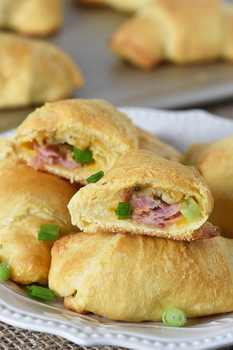 leftover ham recipe made with crescent rolls, crescent roll appetizers stacked on a white plate and cookie sheet
