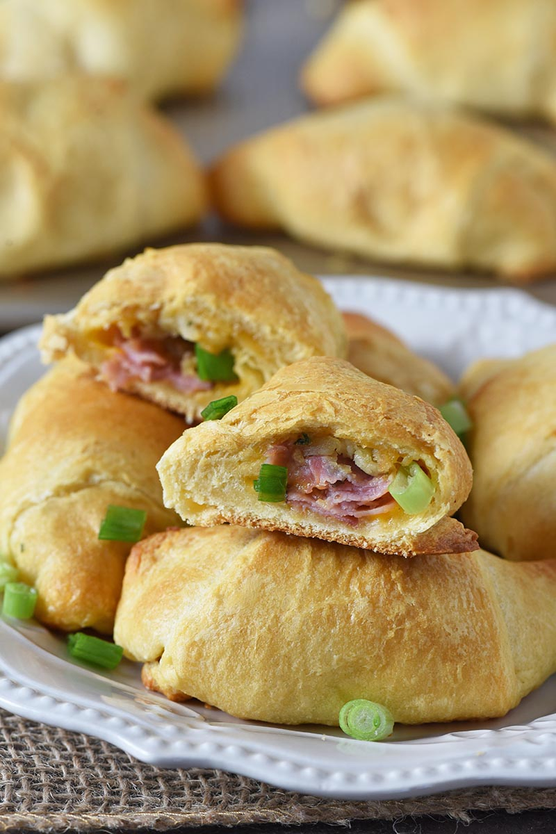pile of leftover ham crescent rolls on white plate with a sprinkling of green onions