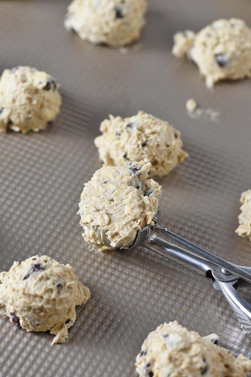 cookie scoop with oatmeal chocolate chip cookie dough on cookie sheet