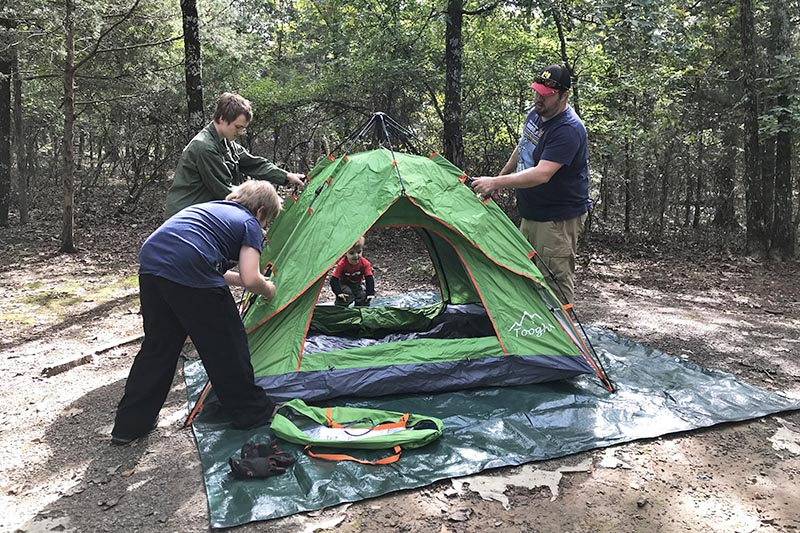setting up a green pop up tent in Petit Jean State Park Campground in Arkansas