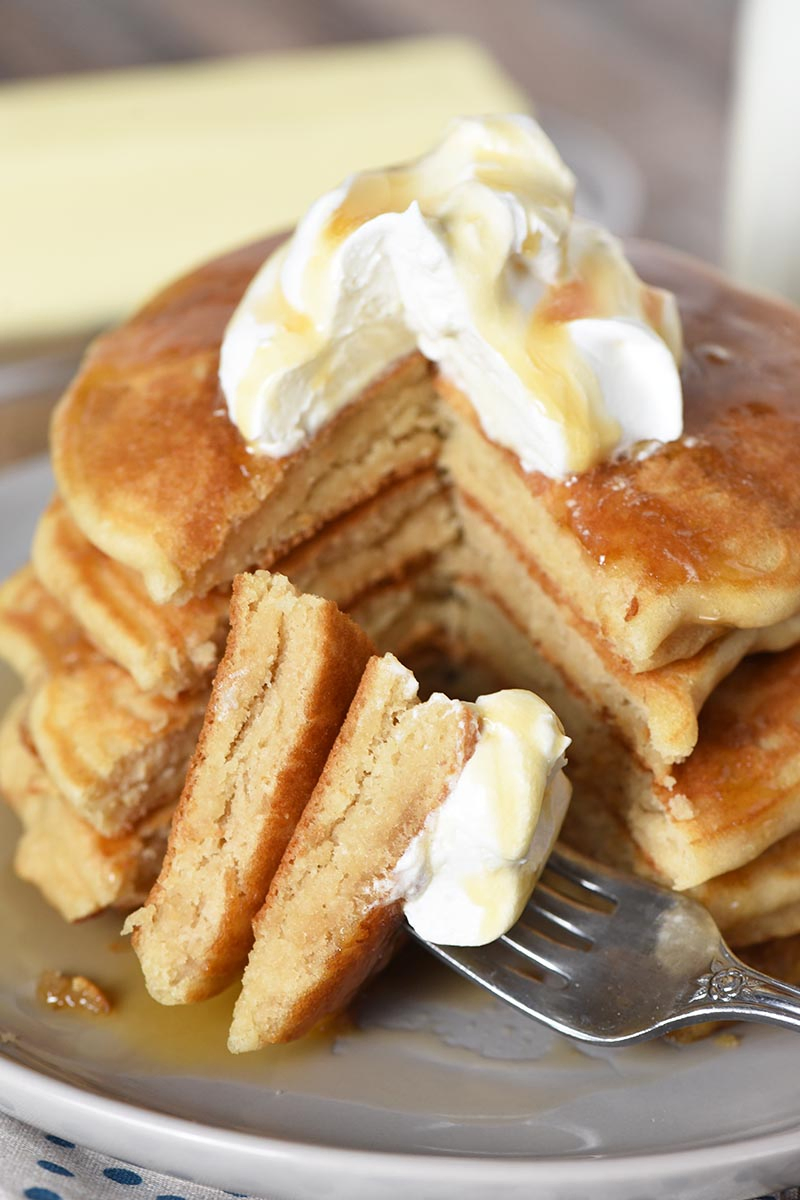 bite of butterbeer pancakes sliced on fork with whipped cream and butterscotch syrup