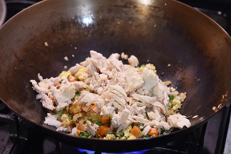 stirring chicken into chicken fried rice mixture in large wok