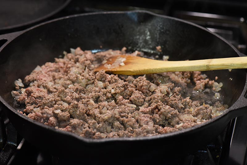 cooking ground beef for tater tot hamburger casserole in cast iron skillet