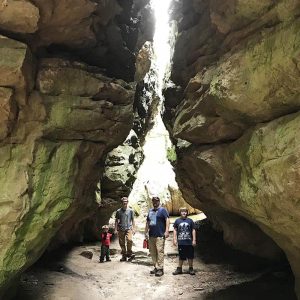 Family standing in Eye of the Needle on Bear Cave Trail in Petit Jean State Park in Arkansas