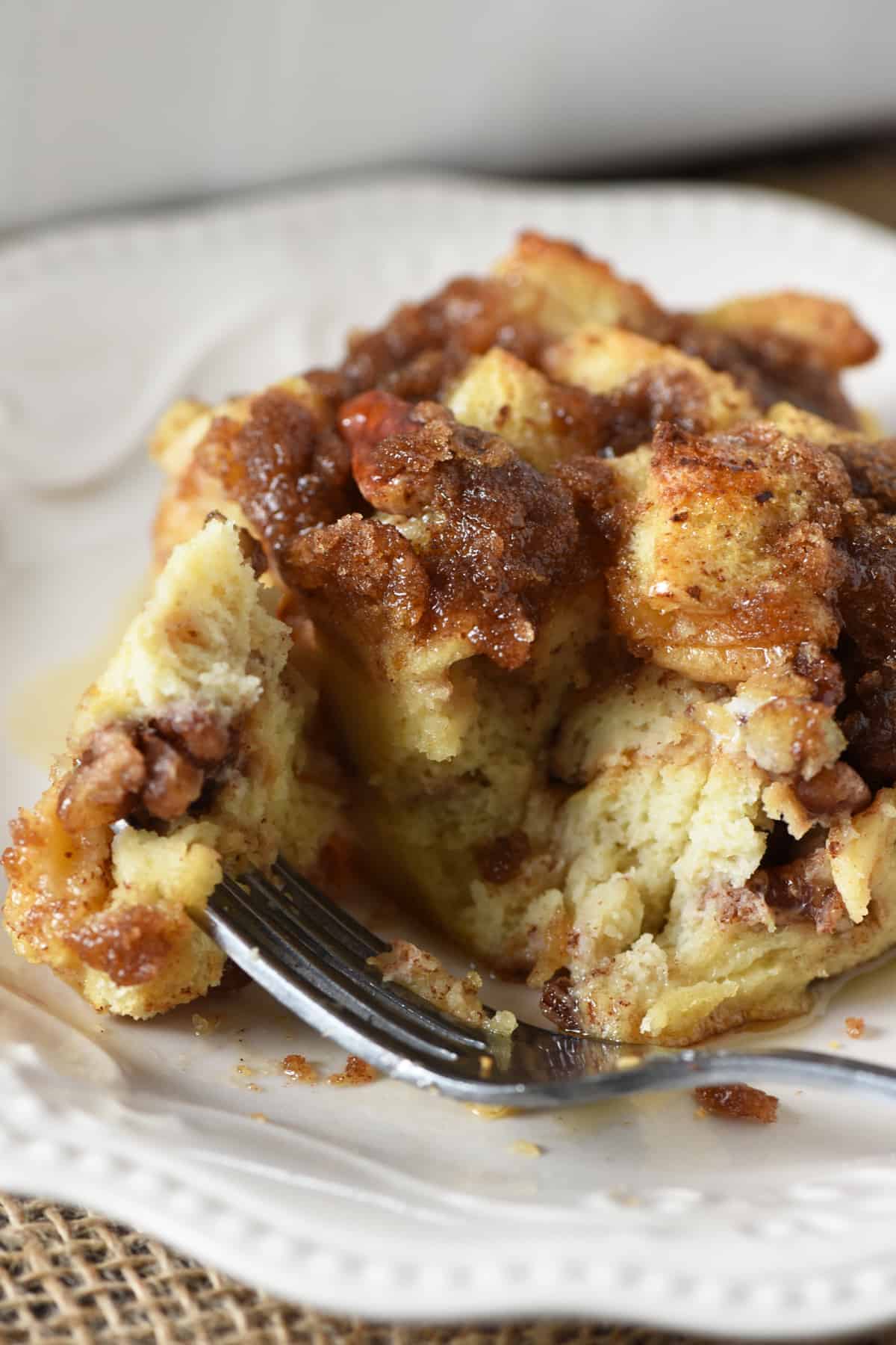 slice and bite of cinnamon French toast bake with fork on white plate