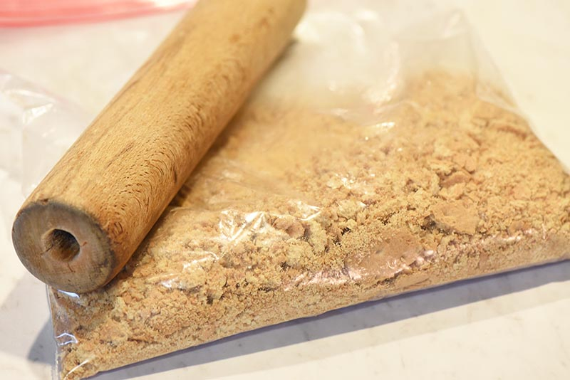 crushing graham crackers for a graham cracker crust, with a rolling pin and Ziploc bag