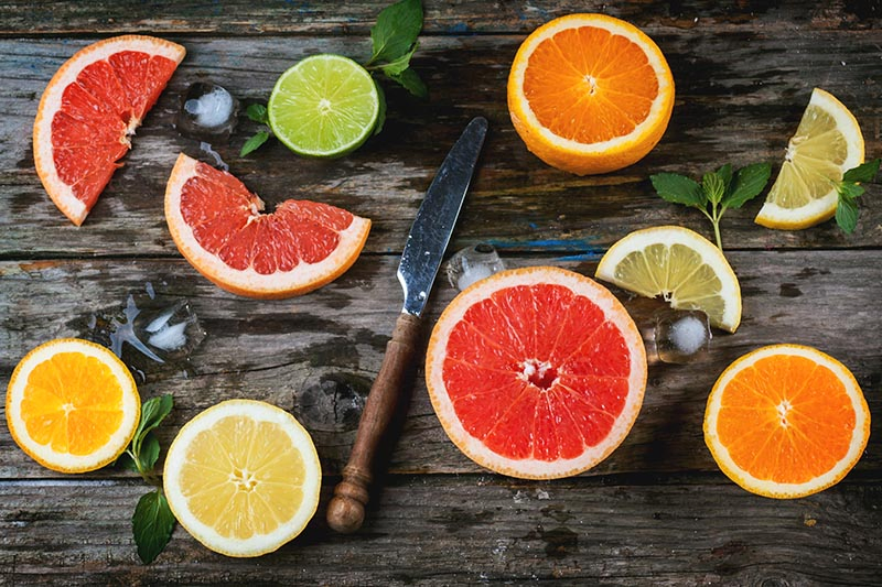 Citrus fruits on a cutting board with a knife
