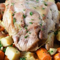 pork roast in oven with potatoes and carrots in a cast iron pan