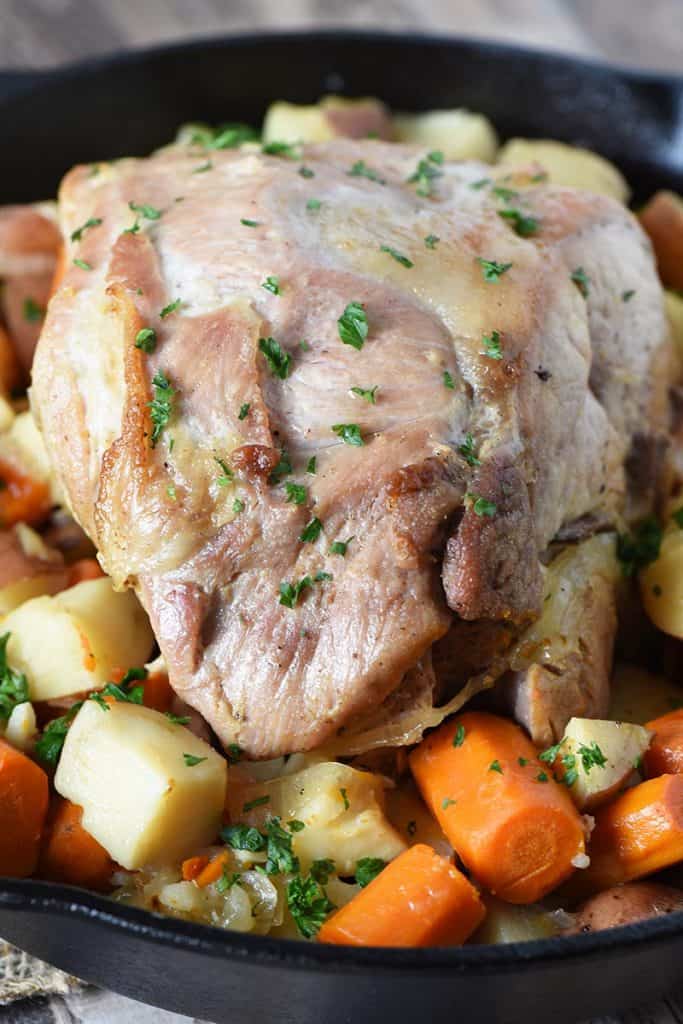pork roast in oven with potatoes and carrots in a cast iron pan