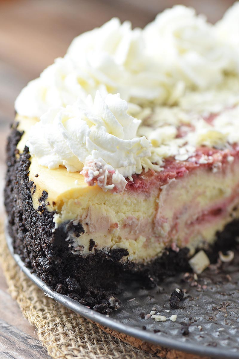 sliced white chocolate raspberry cheesecake with a raspberry swirl and chocolate cookie crust