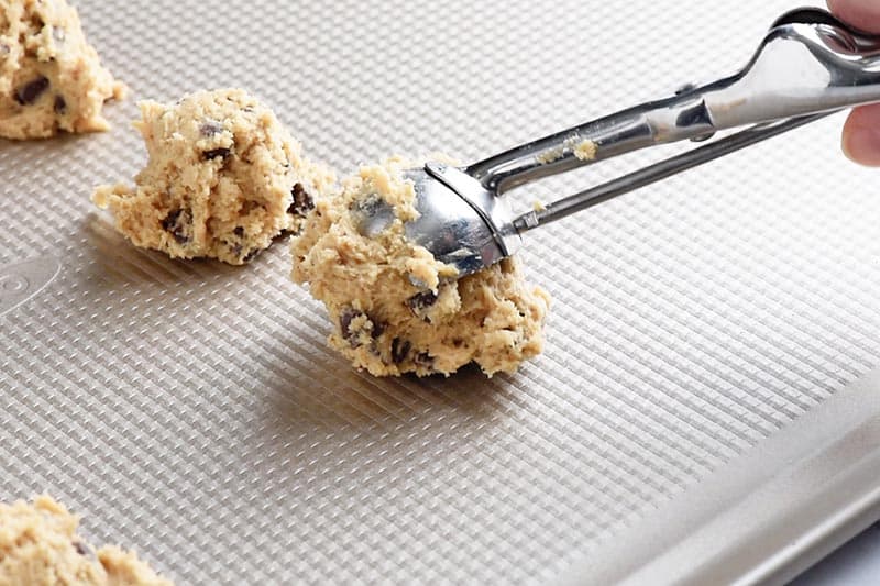 scooping chocolate chip cookie dough onto cookie sheet