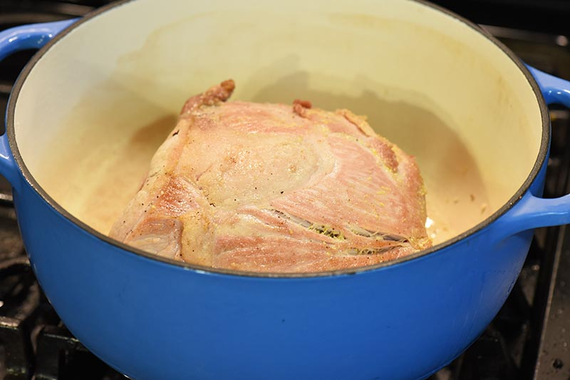 searing pork roast in blue Dutch oven on stovetop
