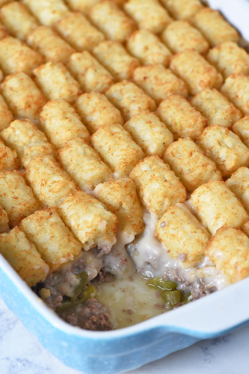 layers of tater tot casserole in blue and white casserole dish