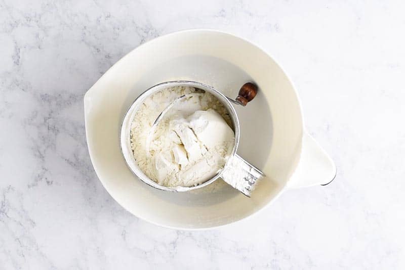 sift dry ingredients into white mixing bowl for chocolate chip cookie recipe