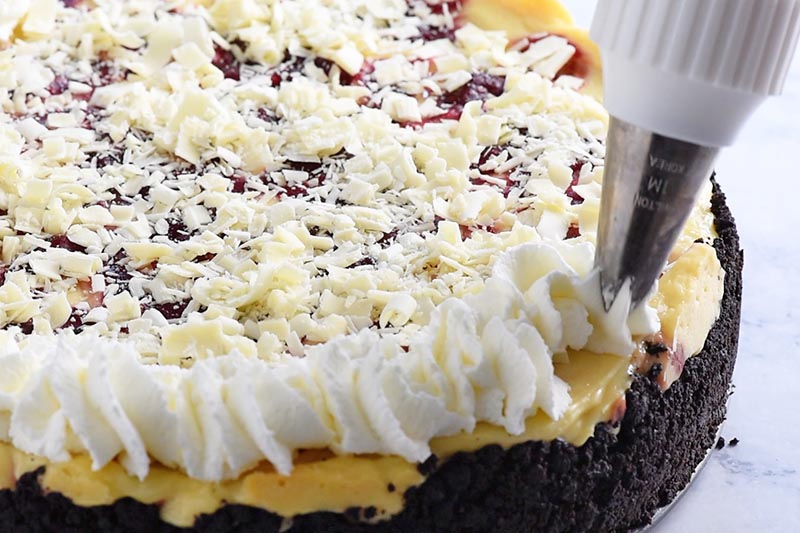swirling whipped cream onto white chocolate raspberry cheesecake with cake tip