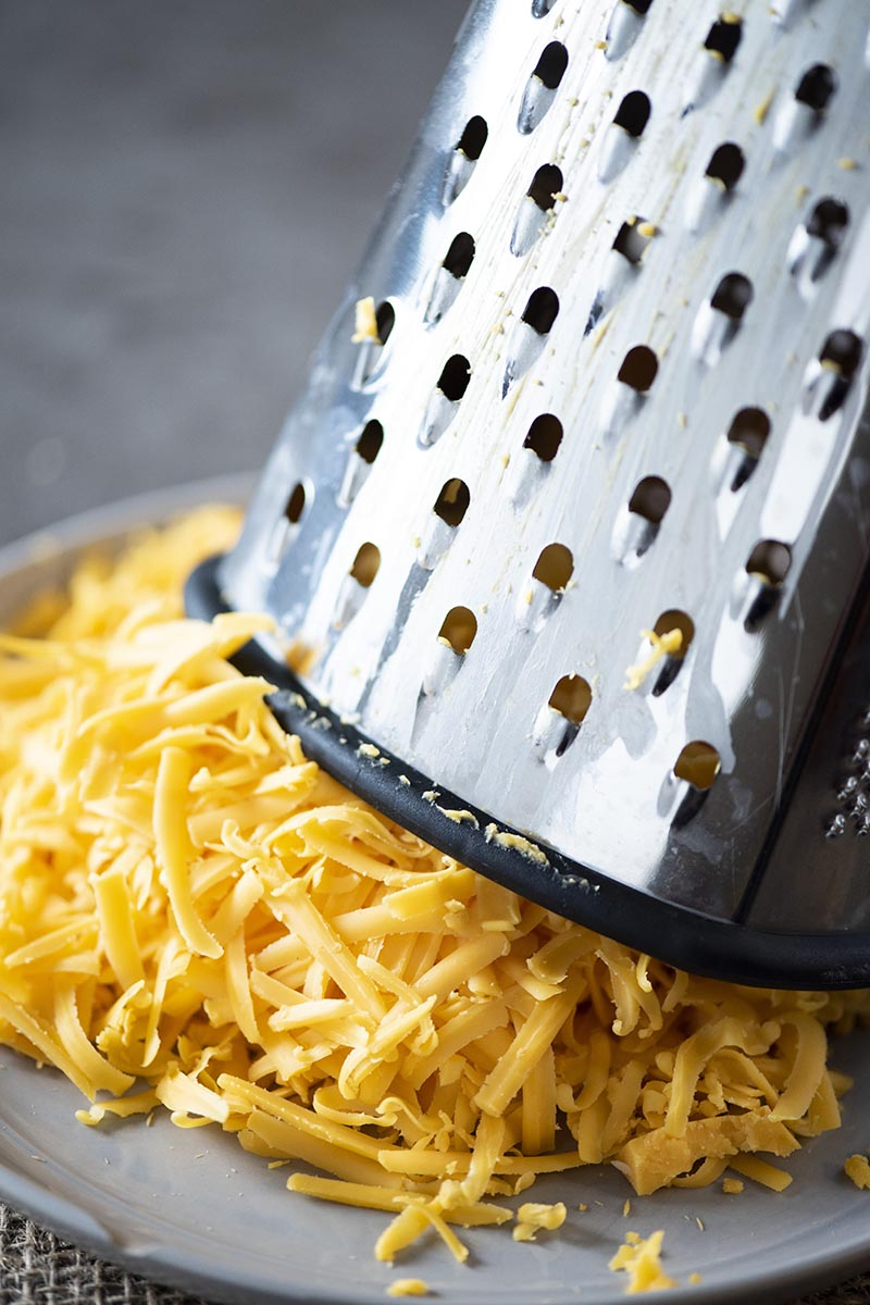 shredded cheese on gray plate with cheese grater