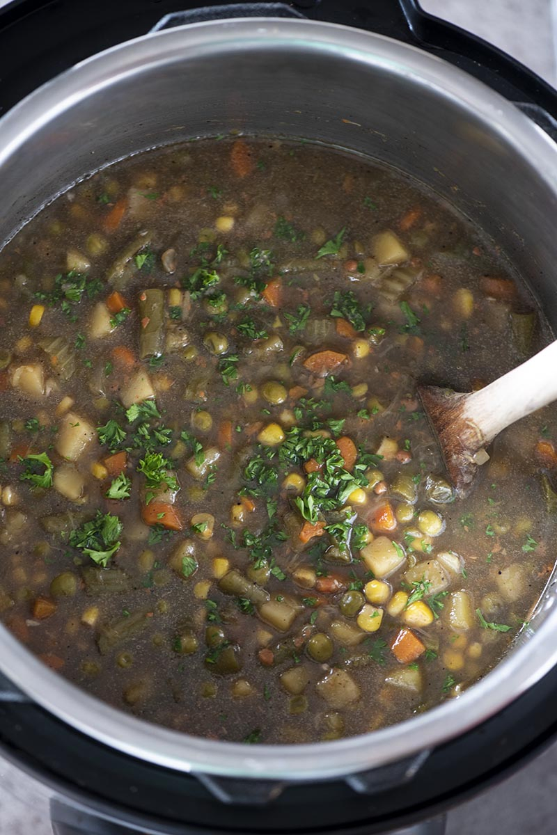 cooked vegetable soup in Instant Pot with wooden spoon