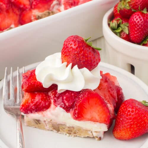 slice of strawberry delight with a pecan crust and a dollop of whipped cream and a fresh strawberry on top