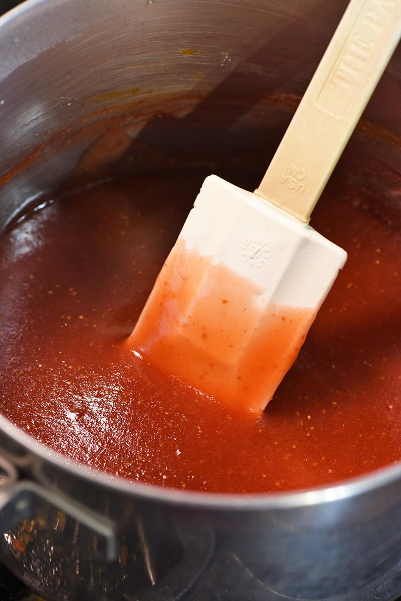 making strawberry sauce for strawberry cheesecake recipe in saucepan with spatula